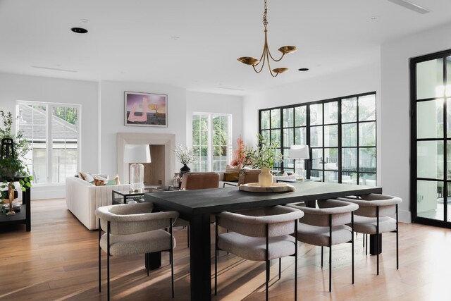 dining room featuring a notable chandelier, light wood-type flooring, and plenty of natural light