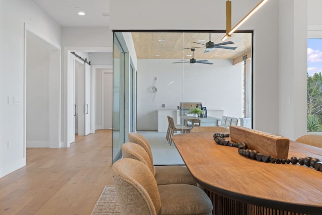 dining room featuring ceiling fan, light wood-type flooring, and a barn door