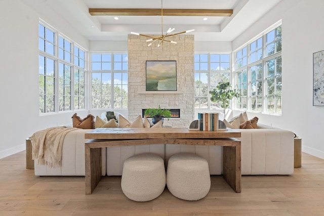 interior space featuring beam ceiling, a chandelier, light hardwood / wood-style floors, and a fireplace