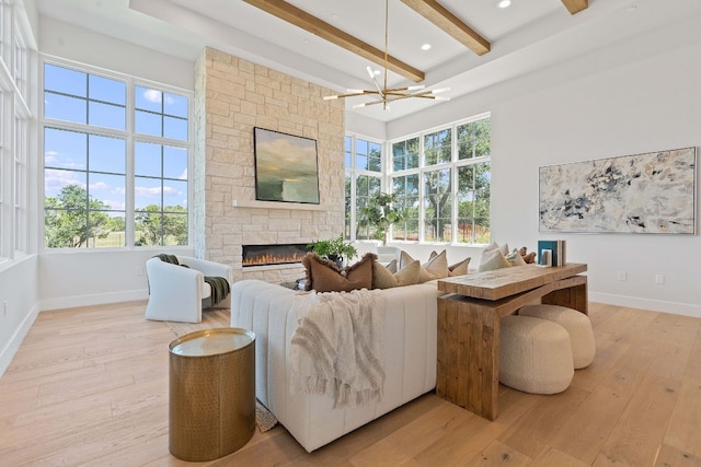 living room featuring beamed ceiling, light hardwood / wood-style flooring, plenty of natural light, and a fireplace