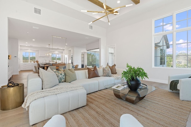 living room featuring a high ceiling, a chandelier, light hardwood / wood-style flooring, and plenty of natural light