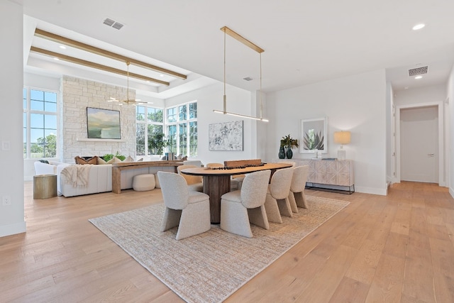 dining room featuring a stone fireplace, an inviting chandelier, and light hardwood / wood-style flooring