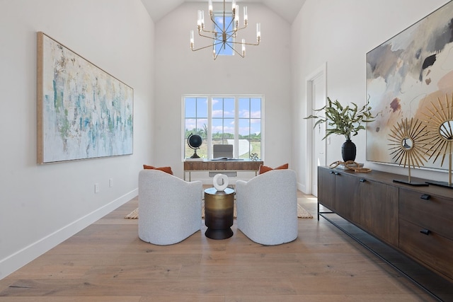 sitting room with an inviting chandelier, light hardwood / wood-style flooring, and high vaulted ceiling