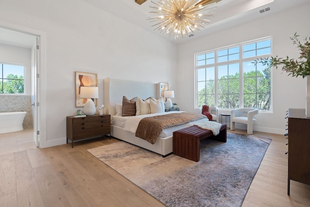 bedroom with ceiling fan with notable chandelier, connected bathroom, and hardwood / wood-style flooring