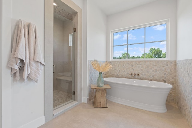 bathroom with shower with separate bathtub, tile patterned flooring, and tile walls