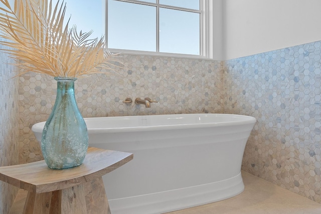 bathroom with a bathing tub, tile walls, and tile patterned floors