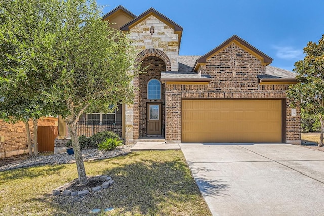 french country inspired facade featuring a garage, brick siding, driveway, and fence