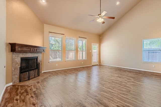 unfurnished living room with a fireplace, wood-type flooring, high vaulted ceiling, and ceiling fan