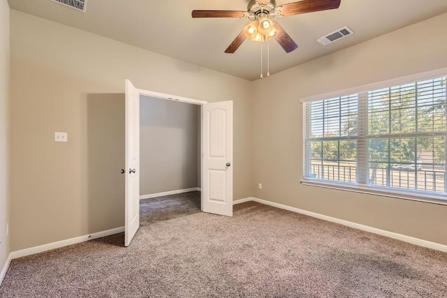 unfurnished bedroom featuring carpet floors, baseboards, visible vents, and ceiling fan