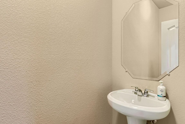 bathroom featuring a textured wall and a sink