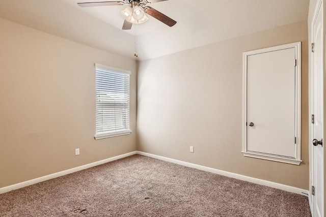 carpeted spare room featuring a ceiling fan and baseboards