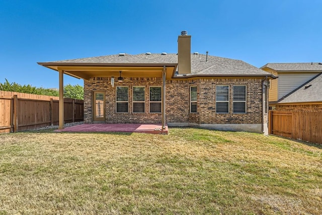 rear view of property featuring a fenced backyard, a yard, brick siding, and a patio