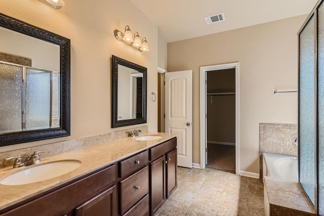 bathroom featuring double vanity, a shower stall, visible vents, and a sink