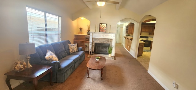 living room with carpet flooring, vaulted ceiling, ceiling fan, and a fireplace