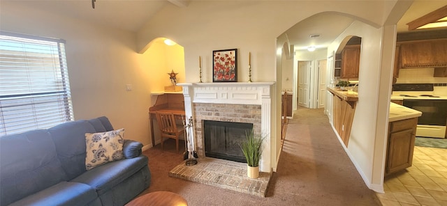 living room featuring a brick fireplace, light colored carpet, and lofted ceiling