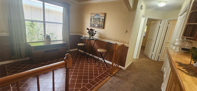 hallway featuring dark carpet and ornamental molding