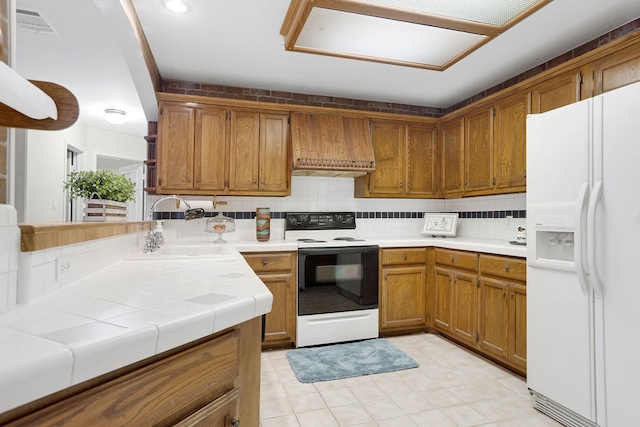 kitchen with tasteful backsplash, sink, white appliances, tile countertops, and premium range hood