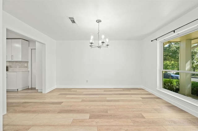 empty room featuring light hardwood / wood-style floors and a notable chandelier