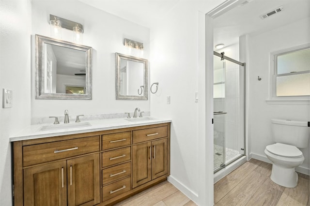 bathroom featuring hardwood / wood-style flooring, vanity, toilet, and a shower with shower door