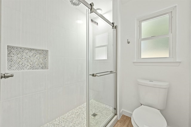 bathroom with hardwood / wood-style flooring, an enclosed shower, and toilet