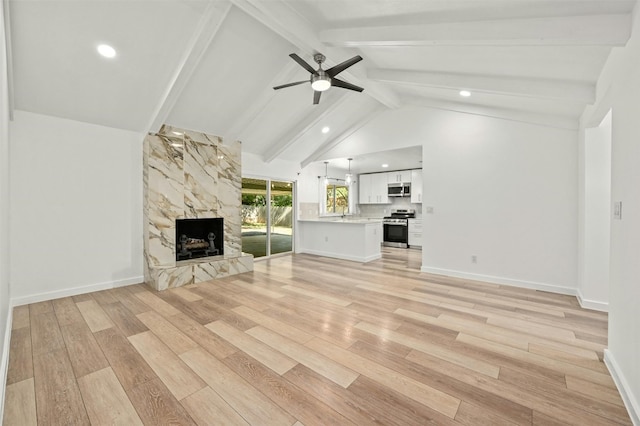 unfurnished living room featuring light hardwood / wood-style flooring, vaulted ceiling with beams, ceiling fan, and a fireplace