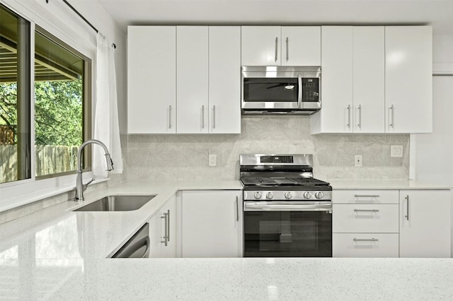 kitchen with white cabinetry, sink, stainless steel appliances, and light stone counters