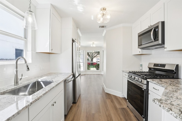 kitchen with stainless steel appliances, white cabinets, and light hardwood / wood-style floors