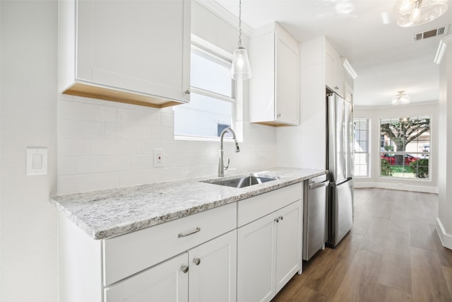 kitchen with pendant lighting, white cabinetry, stainless steel appliances, dark hardwood / wood-style flooring, and light stone countertops