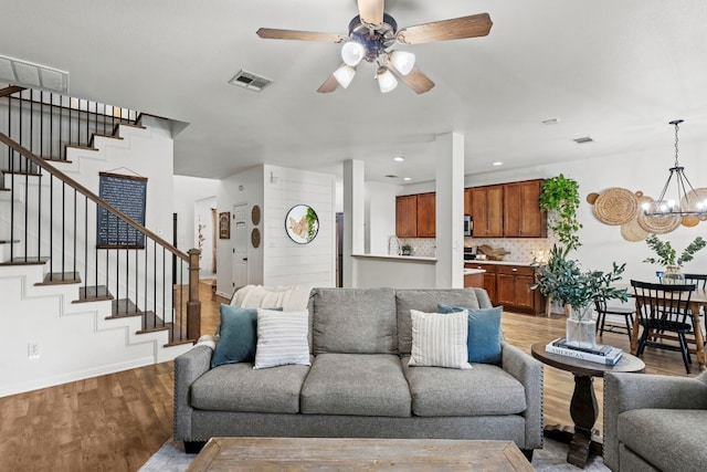 living room with ceiling fan with notable chandelier and light hardwood / wood-style floors