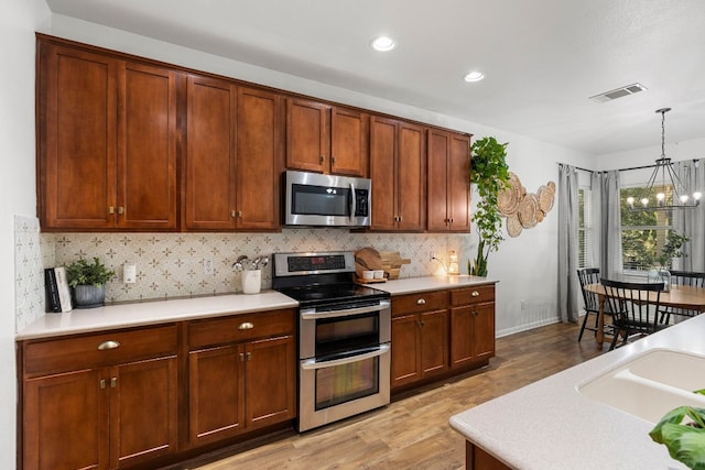 7709 Little Deer Trl, Georgetown, TX 78628 - kitchen with visible vents, stainless steel appliances, a chandelier, light wood-style floors, and backsplash