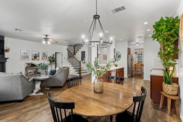 7709 Little Deer Trl, Georgetown, TX 78628 - dining room featuring stairway, visible vents, wood finished floors, and ceiling fan with notable chandelier
