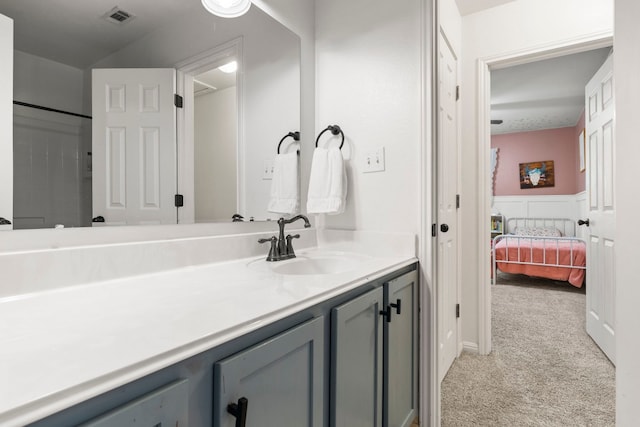 full bath featuring visible vents, wainscoting, connected bathroom, vanity, and walk in shower