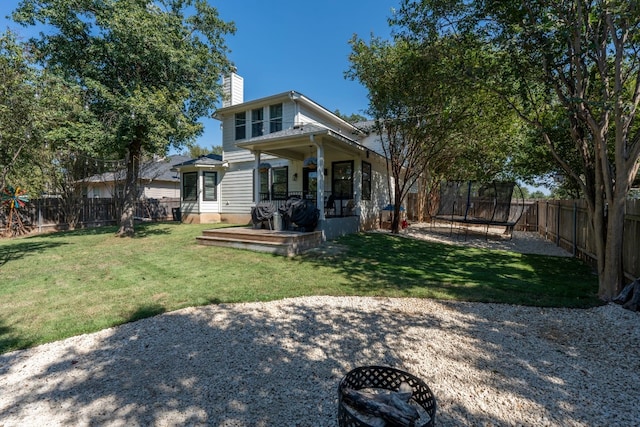 7709 Little Deer Trl, Georgetown, TX 78628 - back of house featuring a chimney, a trampoline, a fenced backyard, and a lawn