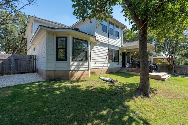 rear view of property featuring a yard and fence