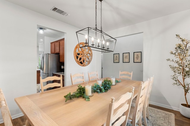 dining area featuring a notable chandelier, baseboards, visible vents, and wood finished floors