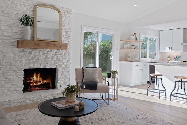 sitting room featuring light hardwood / wood-style flooring, lofted ceiling, a fireplace, and a healthy amount of sunlight