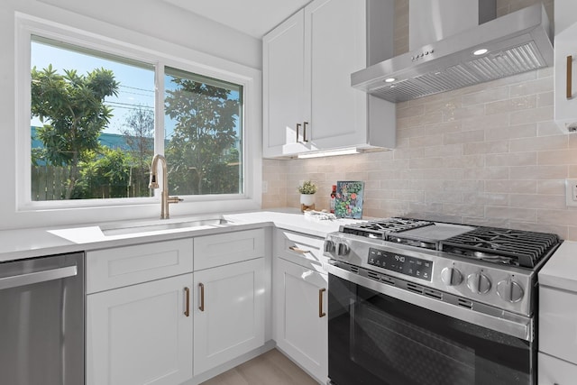 kitchen featuring wall chimney exhaust hood, stainless steel appliances, white cabinets, and sink