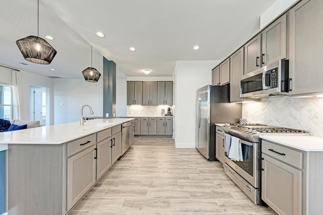 kitchen with gray cabinets, tasteful backsplash, sink, appliances with stainless steel finishes, and decorative light fixtures