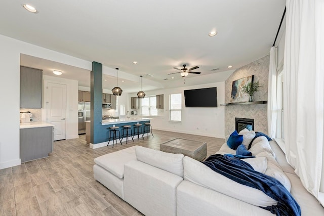 living room featuring a fireplace, ceiling fan, and light hardwood / wood-style flooring