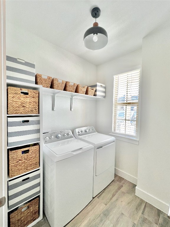 clothes washing area with light hardwood / wood-style flooring and washer and dryer