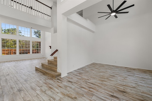 stairs featuring hardwood / wood-style flooring, ceiling fan, and a high ceiling