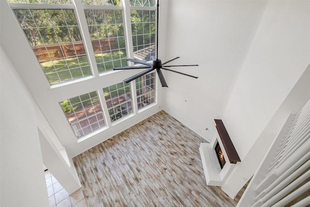 interior space with ceiling fan, a towering ceiling, and a fireplace