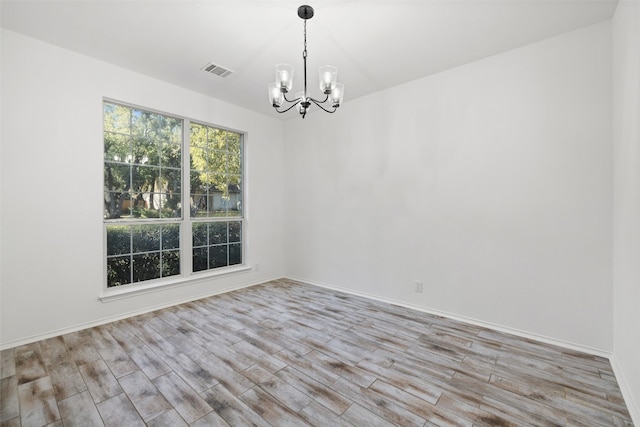 unfurnished room with light wood-type flooring and a chandelier