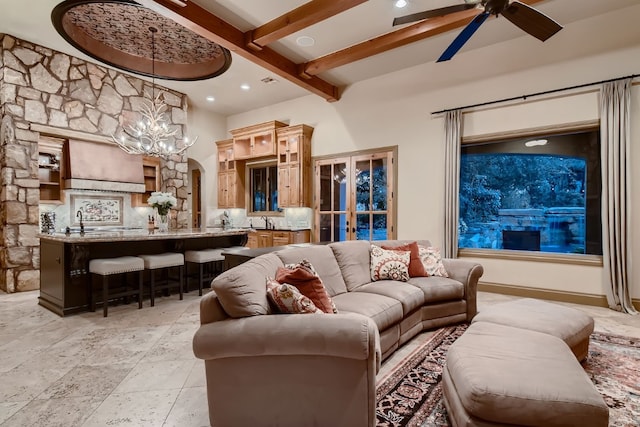 living room with sink, ceiling fan with notable chandelier, and beam ceiling