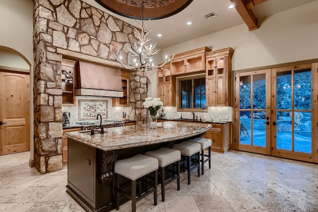 bar with light stone counters, french doors, premium range hood, decorative light fixtures, and backsplash