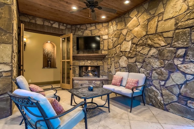 living room featuring ceiling fan, a stone fireplace, light tile patterned flooring, and wood ceiling