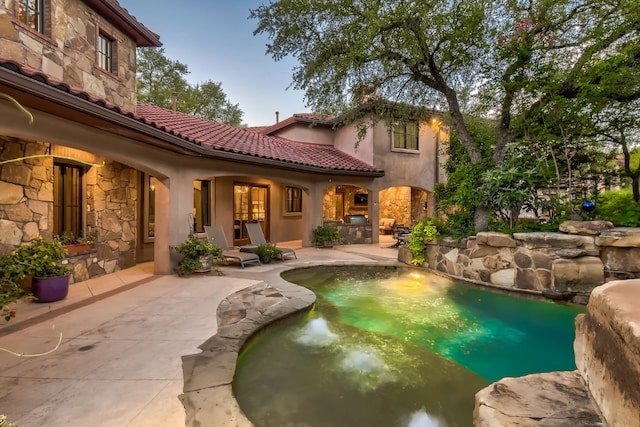 pool at dusk featuring a patio