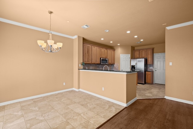 kitchen featuring decorative light fixtures, decorative backsplash, a notable chandelier, kitchen peninsula, and stainless steel appliances