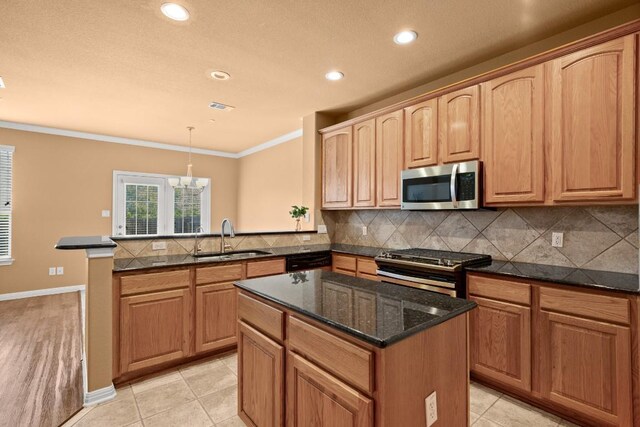 kitchen featuring sink, an inviting chandelier, kitchen peninsula, pendant lighting, and appliances with stainless steel finishes