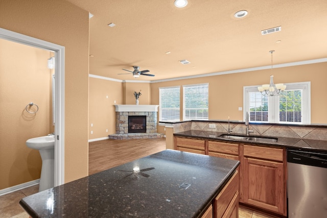 kitchen featuring dishwasher, a fireplace, dark stone countertops, and sink